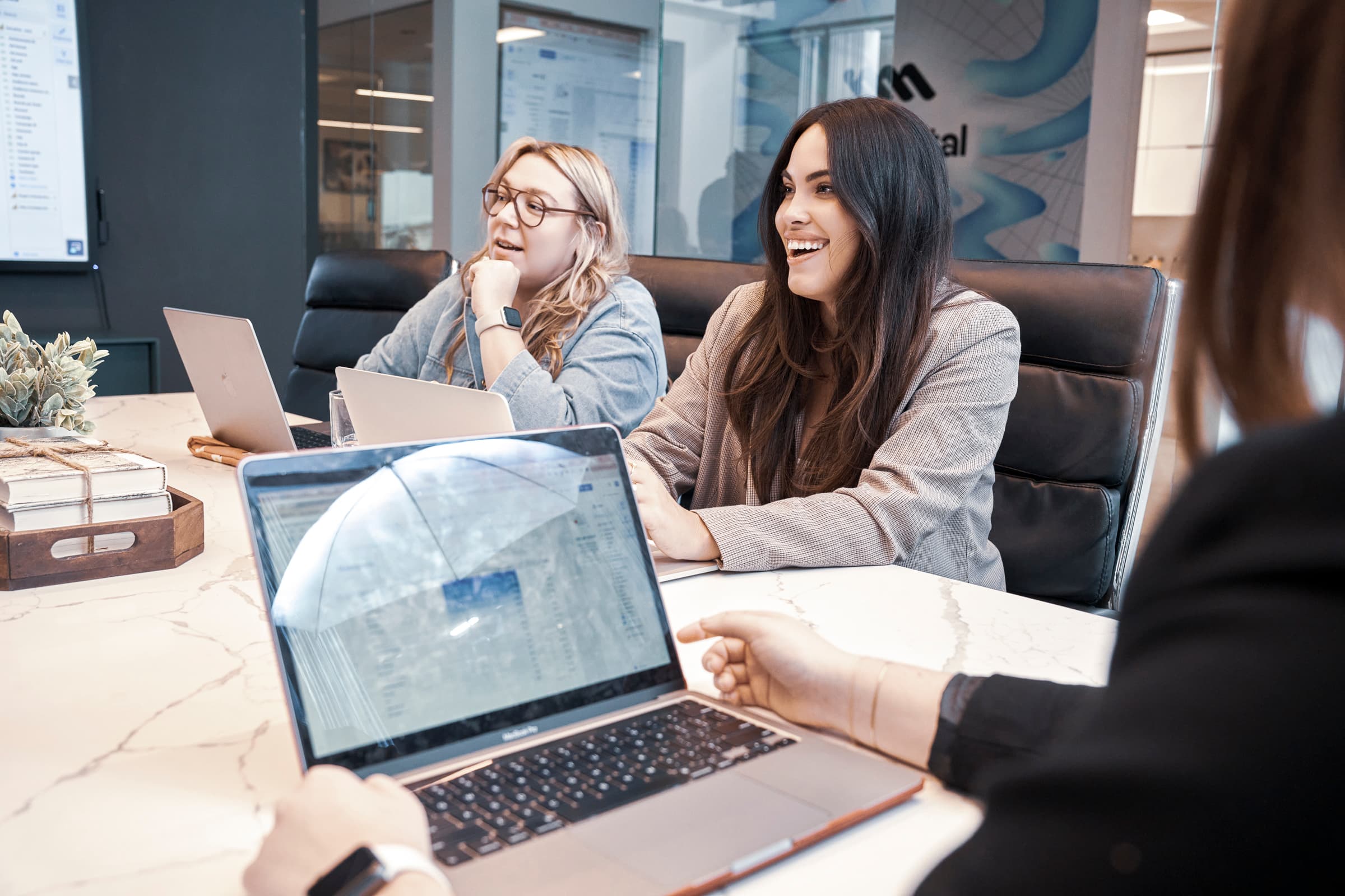 Colleagues smiling while working together on laptops