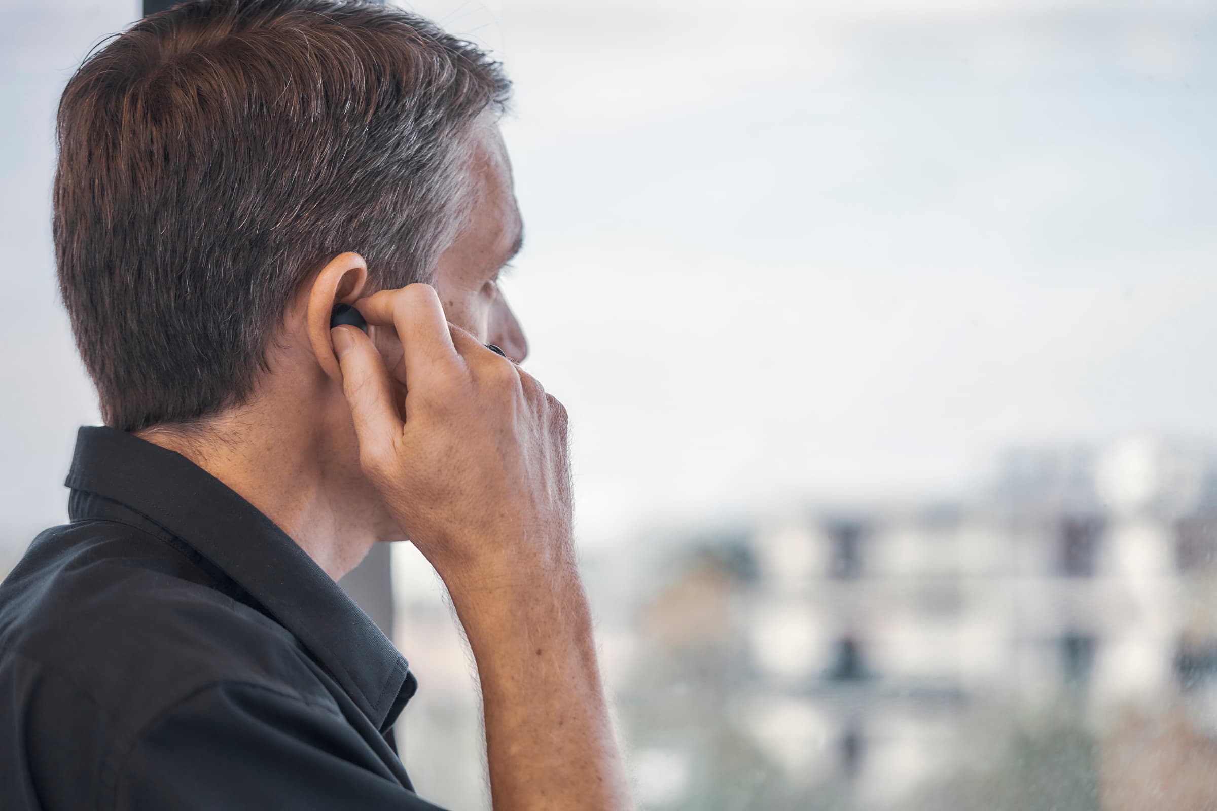 Man inserting a wireless earbud before starting work